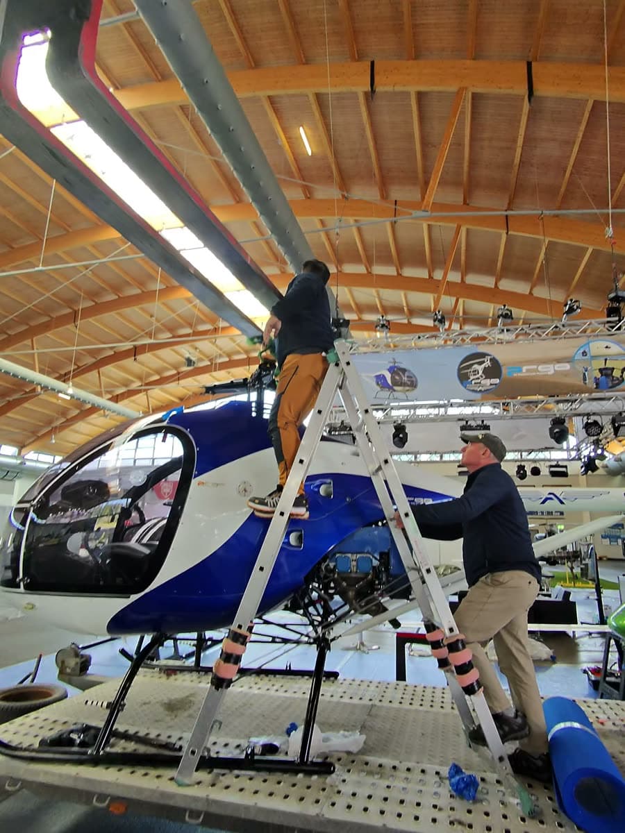 Rigging the lifting sling to the ARGO AH rotor head from a ladder at AERO Friedrichshafen