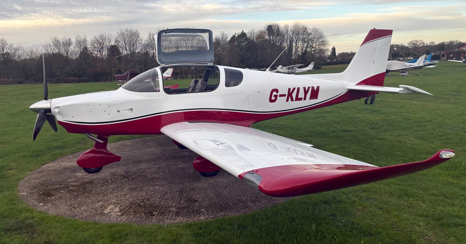 Our own Sling TSi four-seat aircraft on the grass at dusk with the canopy raised